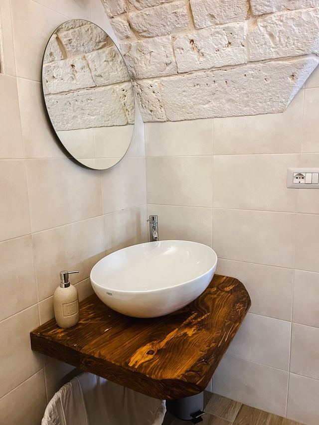 Bagno del Girasole con lavabo in ceramica su mensola in legno massello e specchio tondo