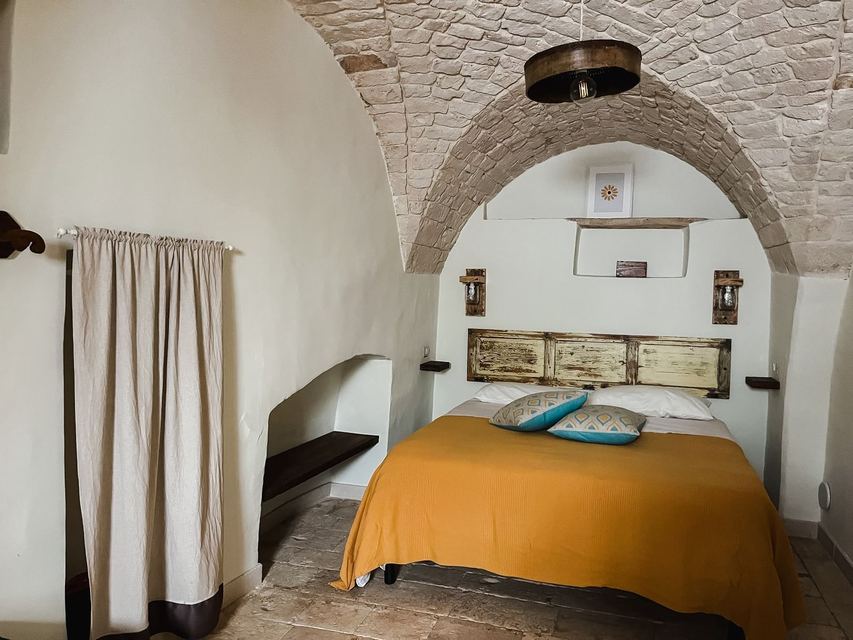 La camera matrimoniale del Girasole vista d'insieme, con arco in pietra, nicchia in muratura e cuscini decorativi