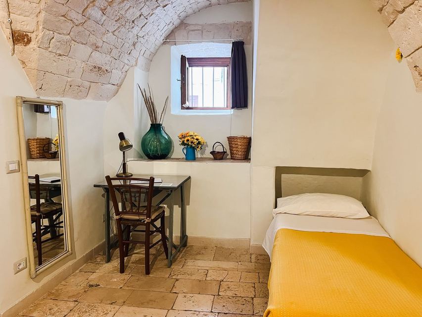 Cameretta del Girasole con letto singolo, scrittoio, specchio e finestrella sotto la volta in pietra
