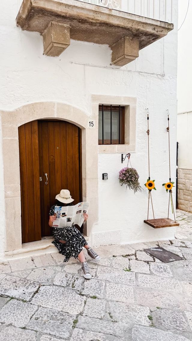 Facciata in calce della casa vacanze il Girasole al civico 15, con portone ad arco in legno e altalena di girasoli