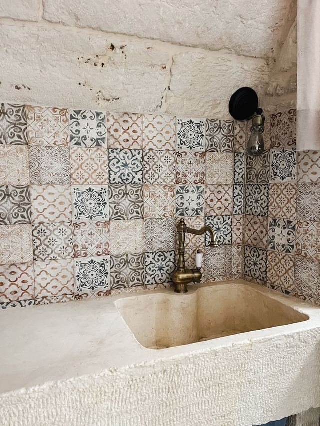 Lavello in pietra con rubinetto in ottone e parete di cementine pugliesi nella casa il Girasole