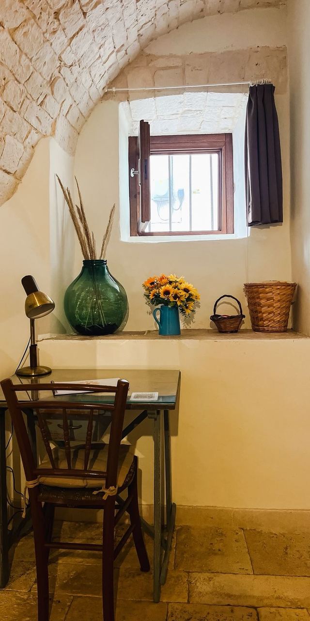 Scrittoio in legno sotto la finestra del Girasole, con lampada e vaso di girasoli